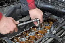 20589373-Mechanic-fixing-spark-plug-to-open-car-engine-with-ratchet-visible-camshafts-pulley-...webp